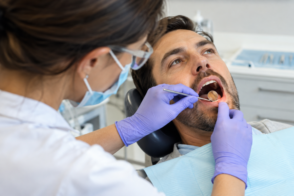 Dentist examining a patient’s lower gums with a dental mirror