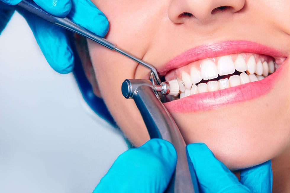 Dental professional examining a patient’s front teeth with a mirror