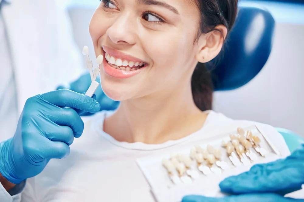 Tooth shade samples held beside a smiling patient’s teeth