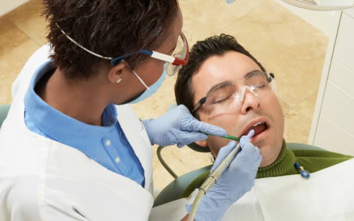 Dental professional examining a reclining patient’s mouth