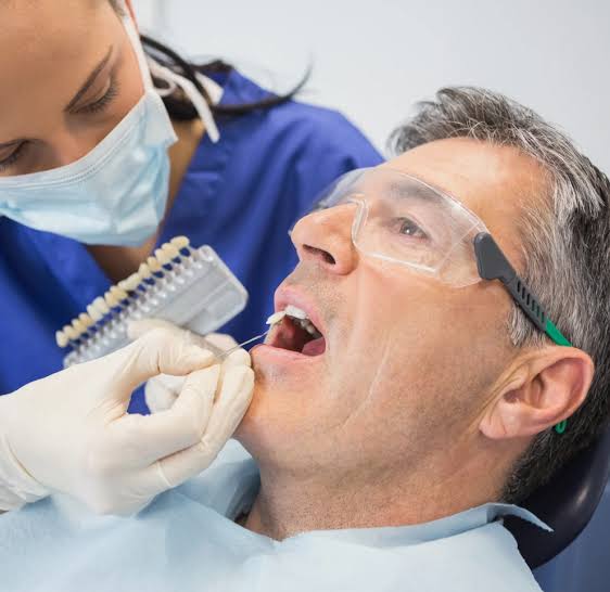Tooth shade guide held beside a patient’s mouth