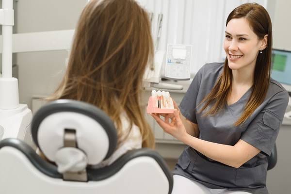 Dental professional showing a teeth model to a seated patient