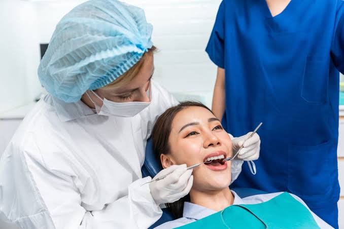 Dental professional examining a patient’s teeth with instruments