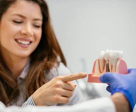 Patient pointing to a dental implant model during a consultation