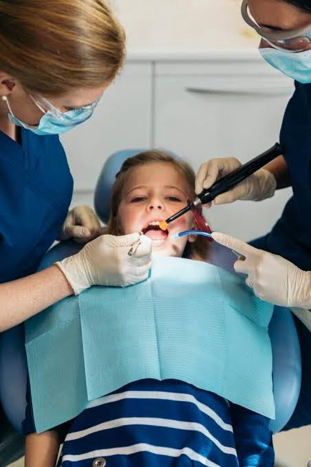 Dental team treating a child in a dental chair