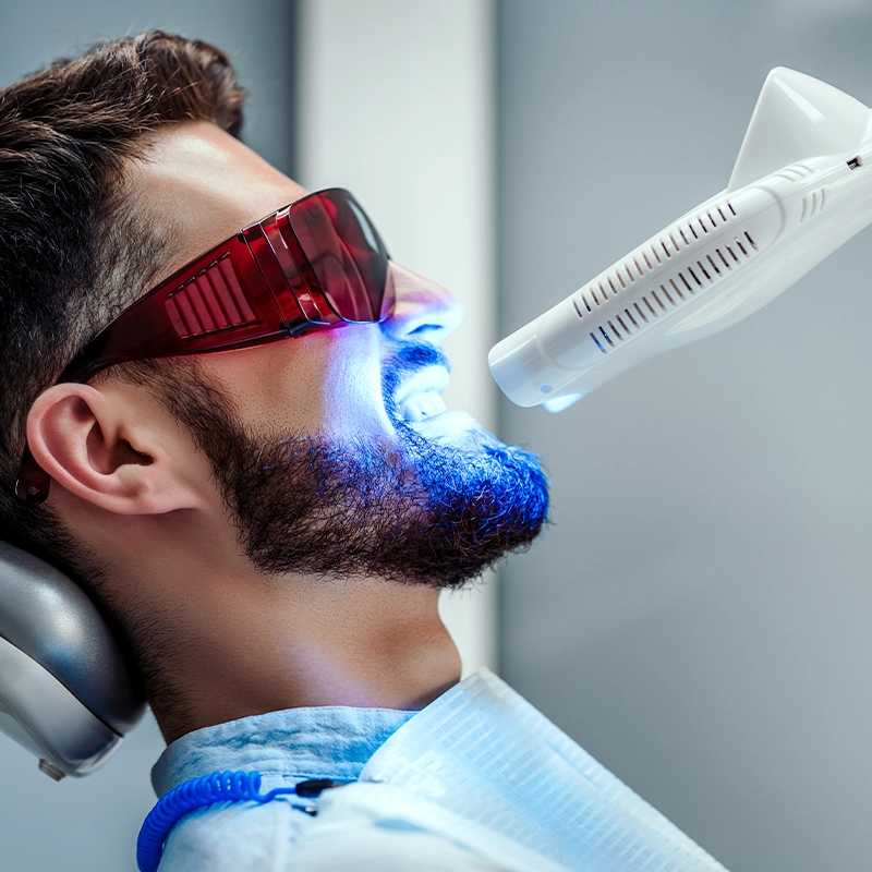 In-office teeth whitening image showing a light directed at a patient’s mouth